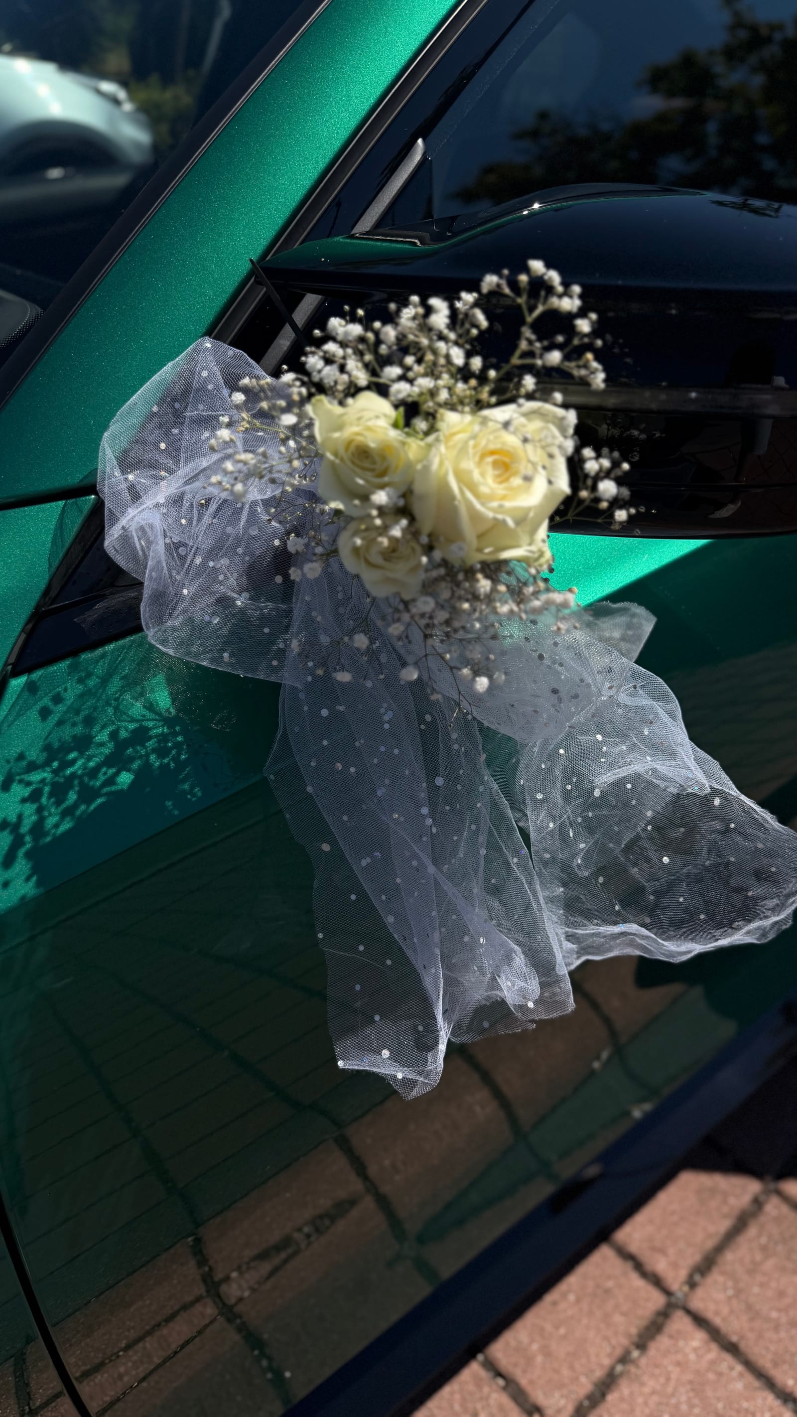 Außenspiegel eines Hochzeitsautos, geschmückt mit Rosen, Schleierkraut und Perlentüll